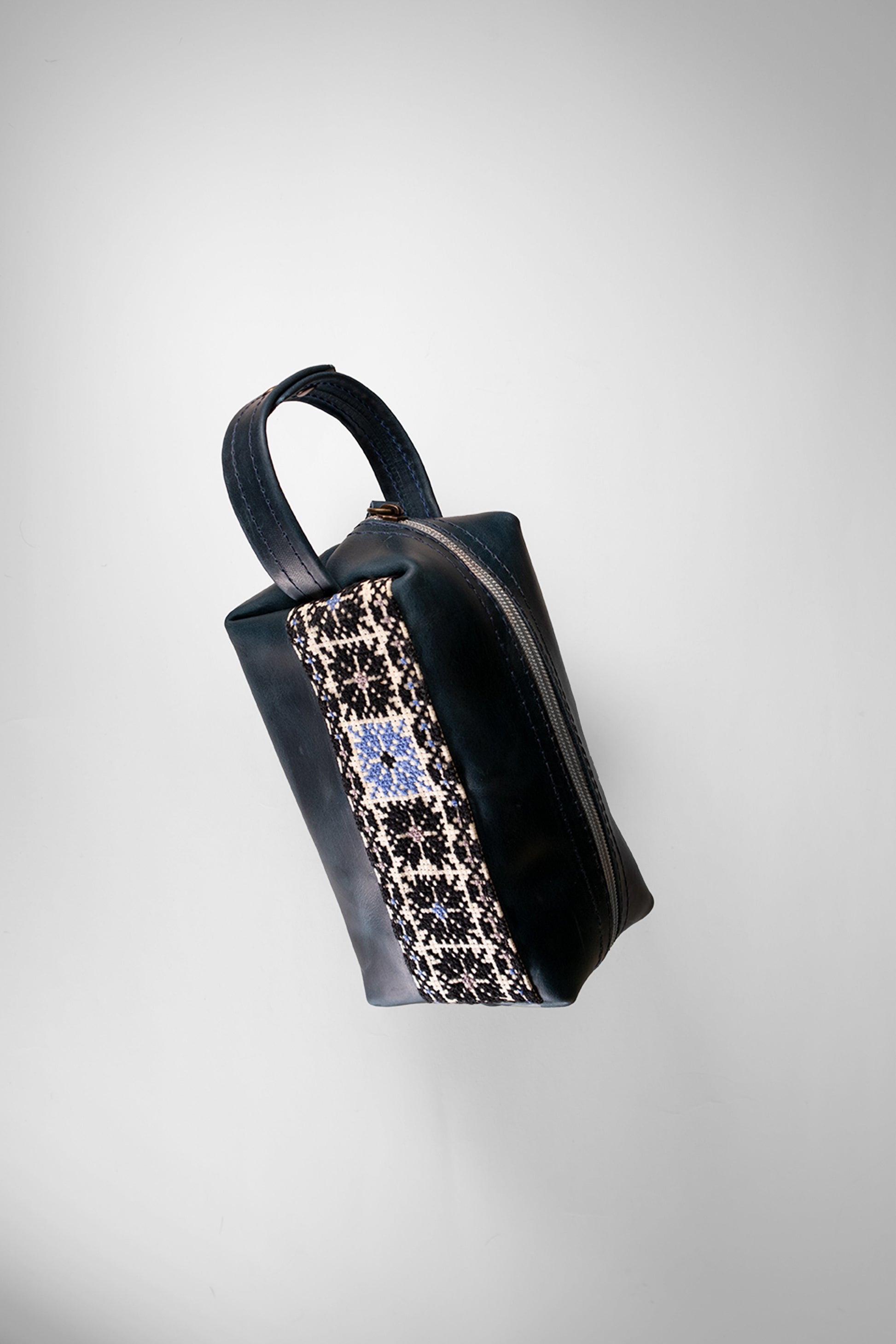 “Handmade leather clutch bag with traditional hand embroidery, crafted in Palestine.”