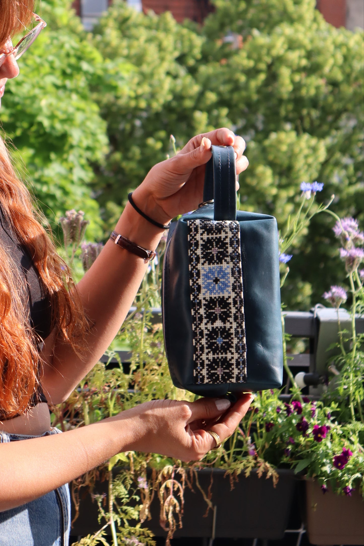 a girl grabbing a Handmade leather clutch bag with traditional hand embroidery, crafted in Palestine-Palistone brand