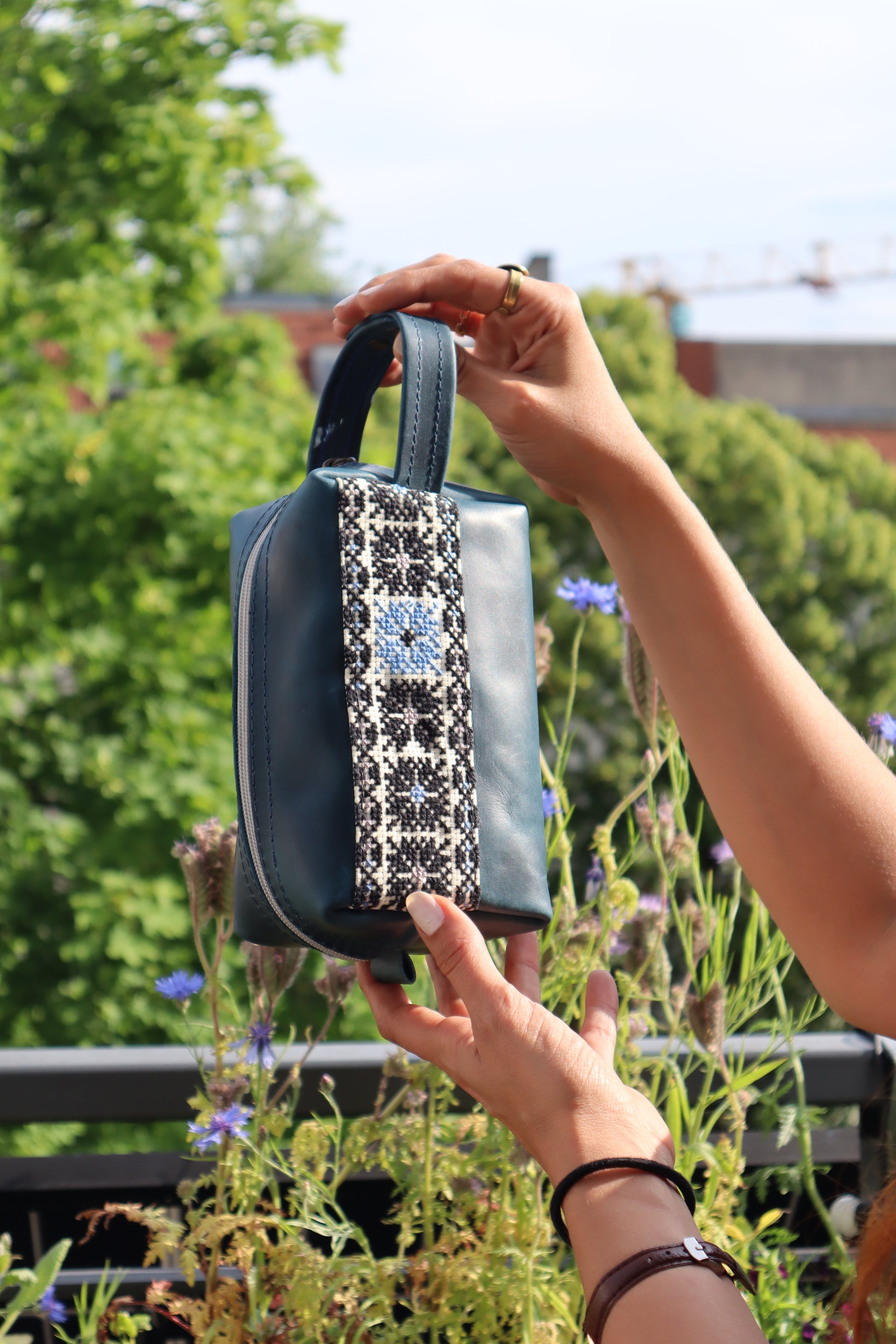 a girl grabbing a Handmade leather clutch bag with traditional hand embroidery, crafted in Palestine-Palistone brand