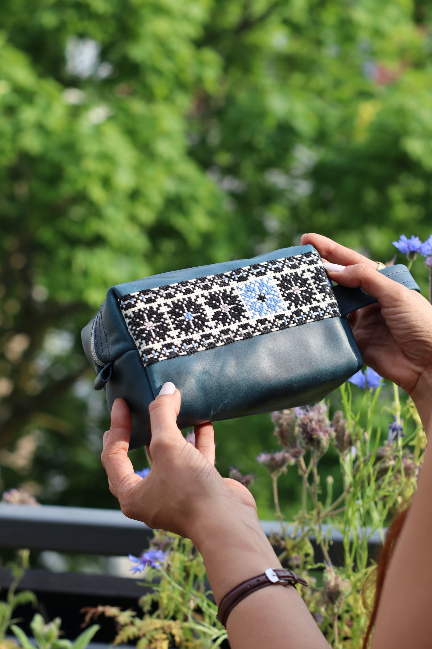 a girl grabbing a Handmade leather clutch bag with traditional hand embroidery, crafted in Palestine-Palistone brand